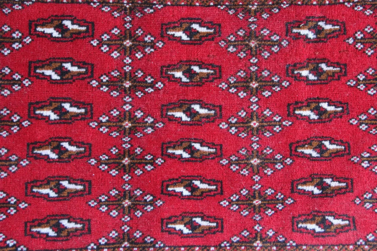 Close-up of a Turkmen carpet: red ground fabric with repeating geometric motifs
