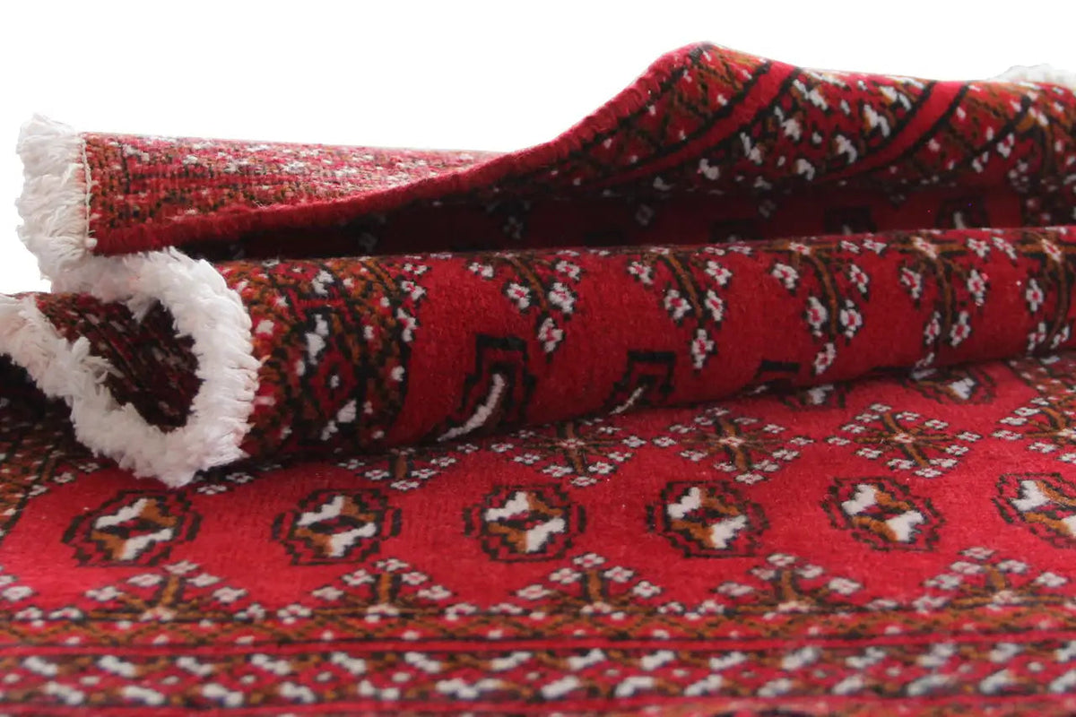 Turkmen carpet side view: turned with a red pattern and white fringes