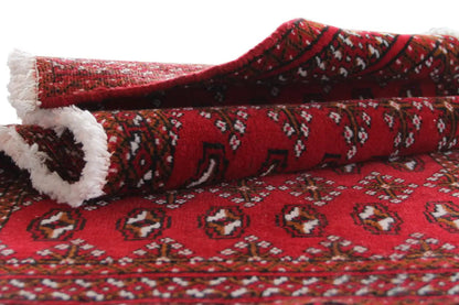 Turkmen carpet side view: turned with a red pattern and white fringes