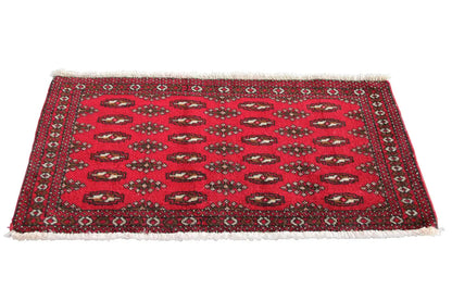 Red patterned Turkmen carpet with small medallions, dark border and fringes
