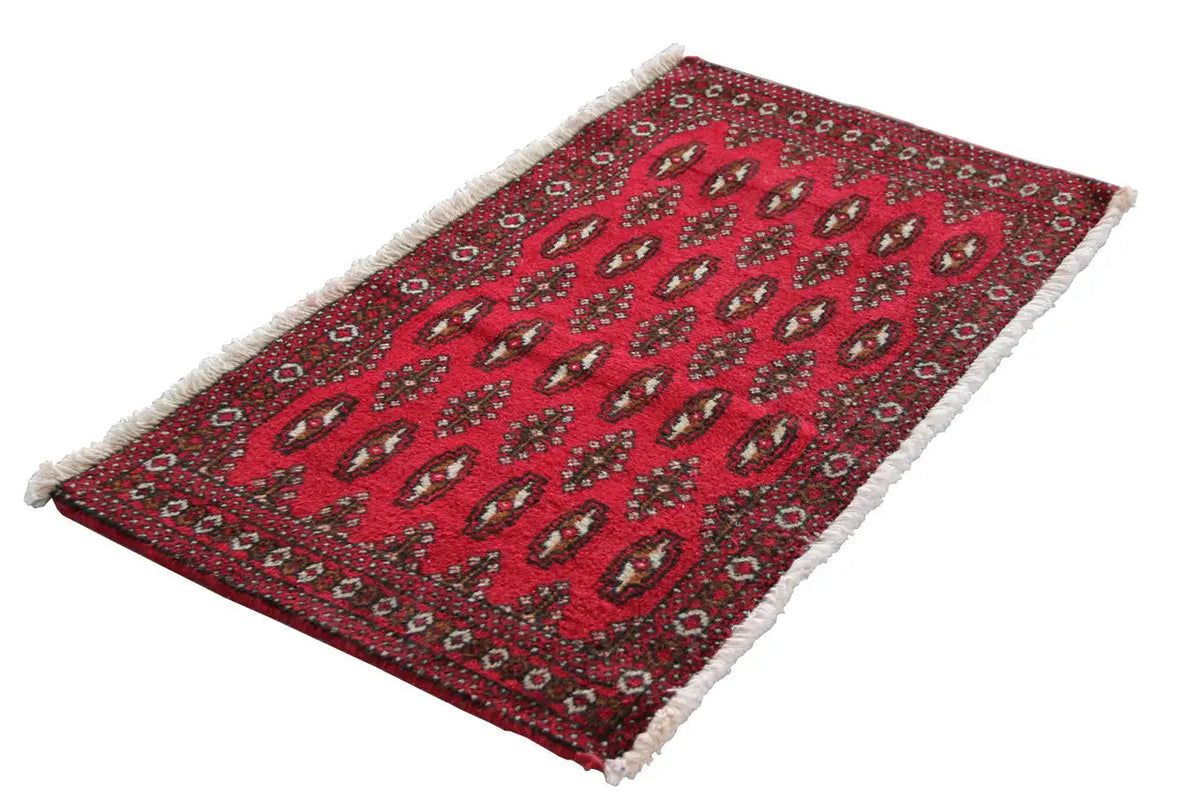 Red Turkmen carpet with decorative rows and white frayed edges