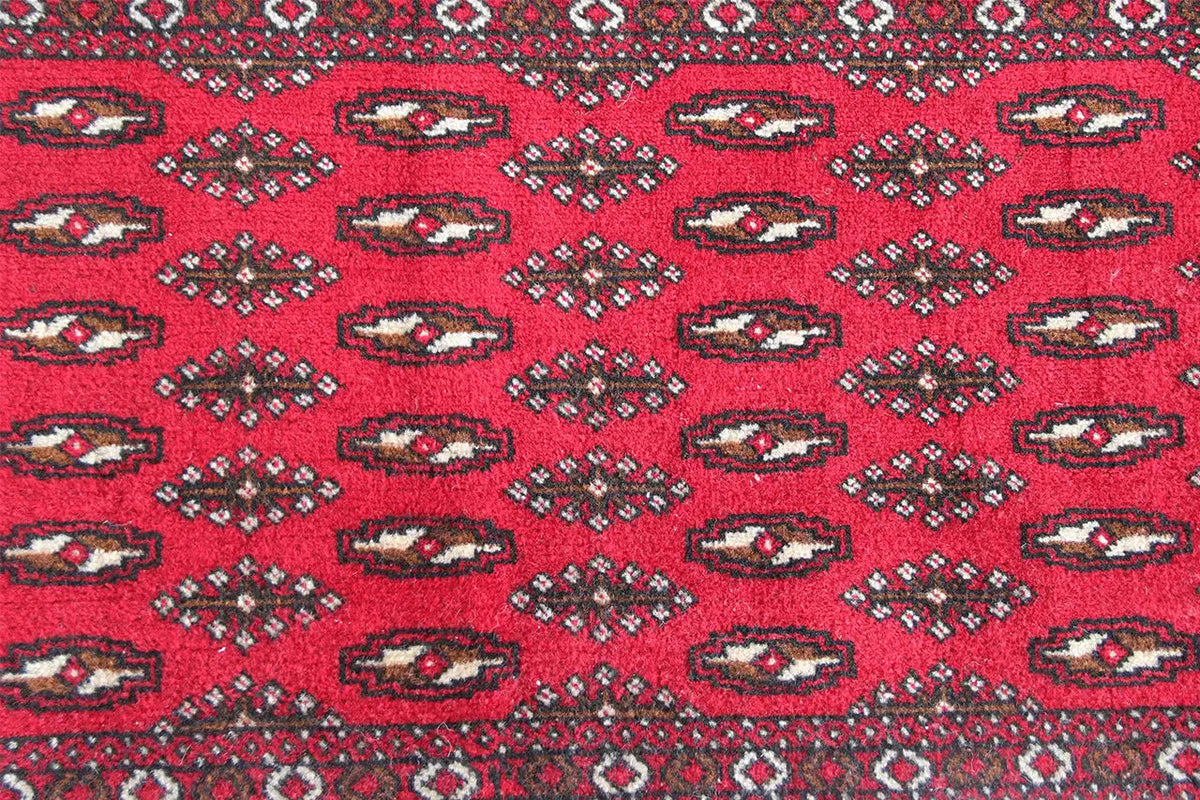 Close-up: red Turkmen carpet with repeating oval motifs in the pattern