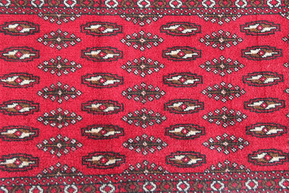 Close-up: red Turkmen carpet with repeating oval motifs in the pattern