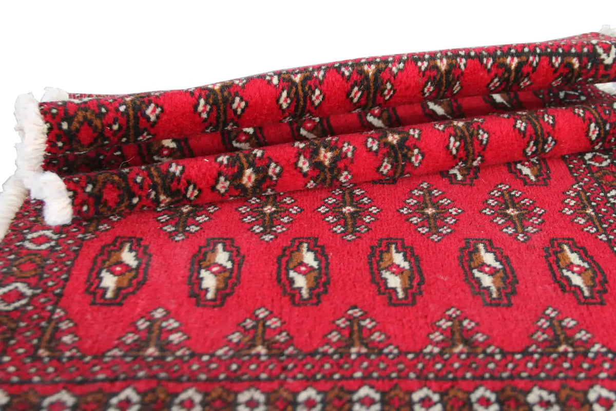 Turkmen carpet rolled out with a red ground and varied ornamental stripes