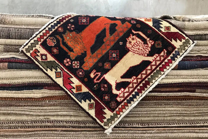 Teppich Poschti Qashqai gefaltet mit orange-schwarzem Tiermuster und dekorativem Rand