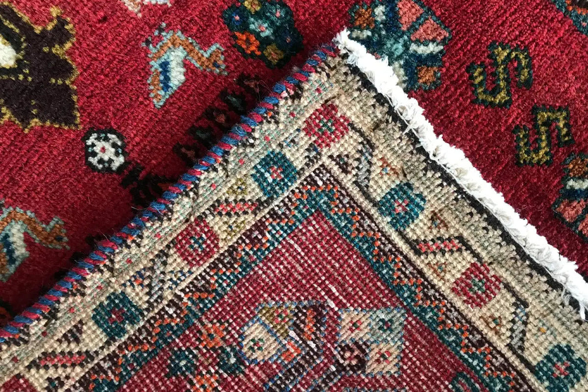 Close-up: red carpet with woven patterns and white trim along the edge