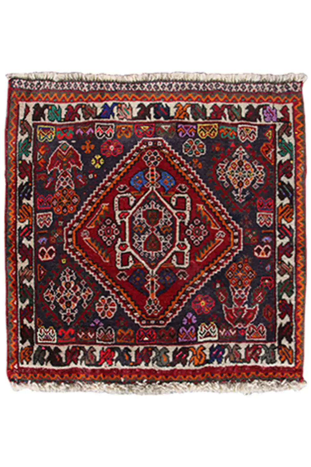 Rug in a 59x59-cm format with an oriental pattern in red, blue, and dark gray, with fringes.