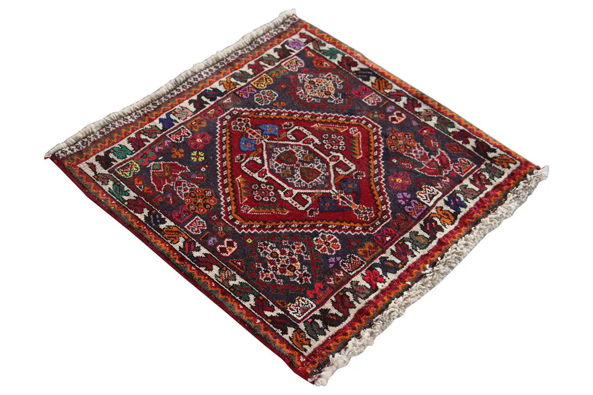 Square rug, diagonal view: dark background with a red medallion and colorful ornaments.