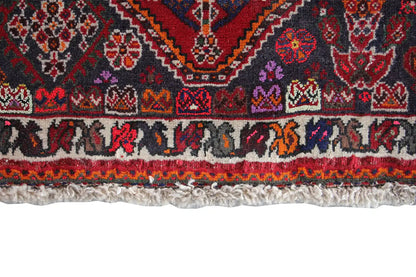 Detailed view of rug edge: multicolored border strip at the bottom and short pile with fringes.