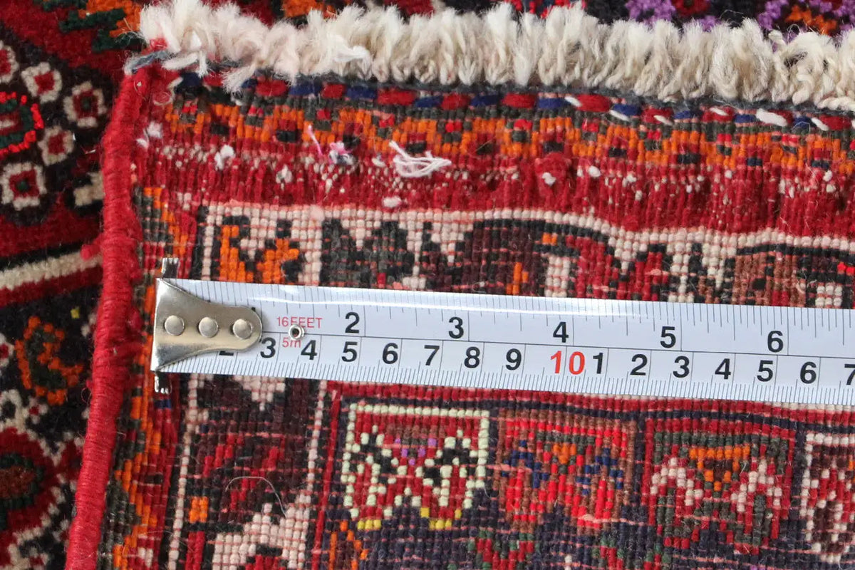 Close-up of carpet edge with measuring tape: length approximately 59 cm, red embroidered trim.