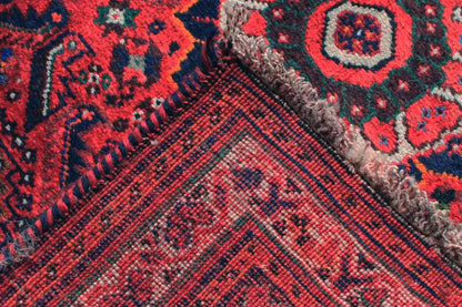 Detail of the oriental runner rug: red and dark blue pattern, multicolored accents, visible pile