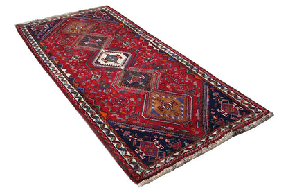 Oriental rug runner spread out in a triangle: red base pattern with multicolored diamonds and border