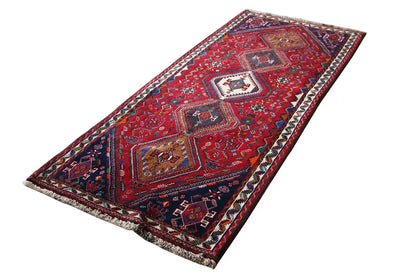 Oriental rug runner in angled view, red ornaments with central medallions, border all around