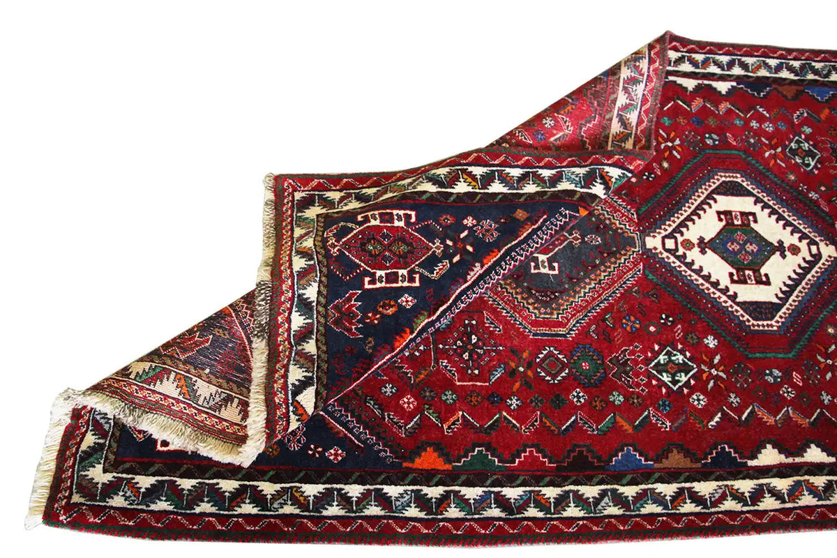 Oriental rug runner with a red background, dark blue sides, and a braided fringe