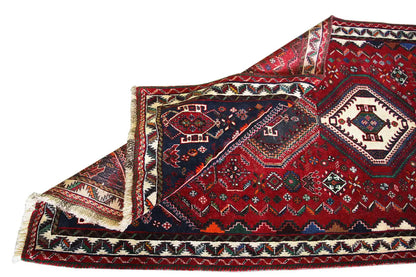 Oriental rug runner with a red background, dark blue sides, and a braided fringe