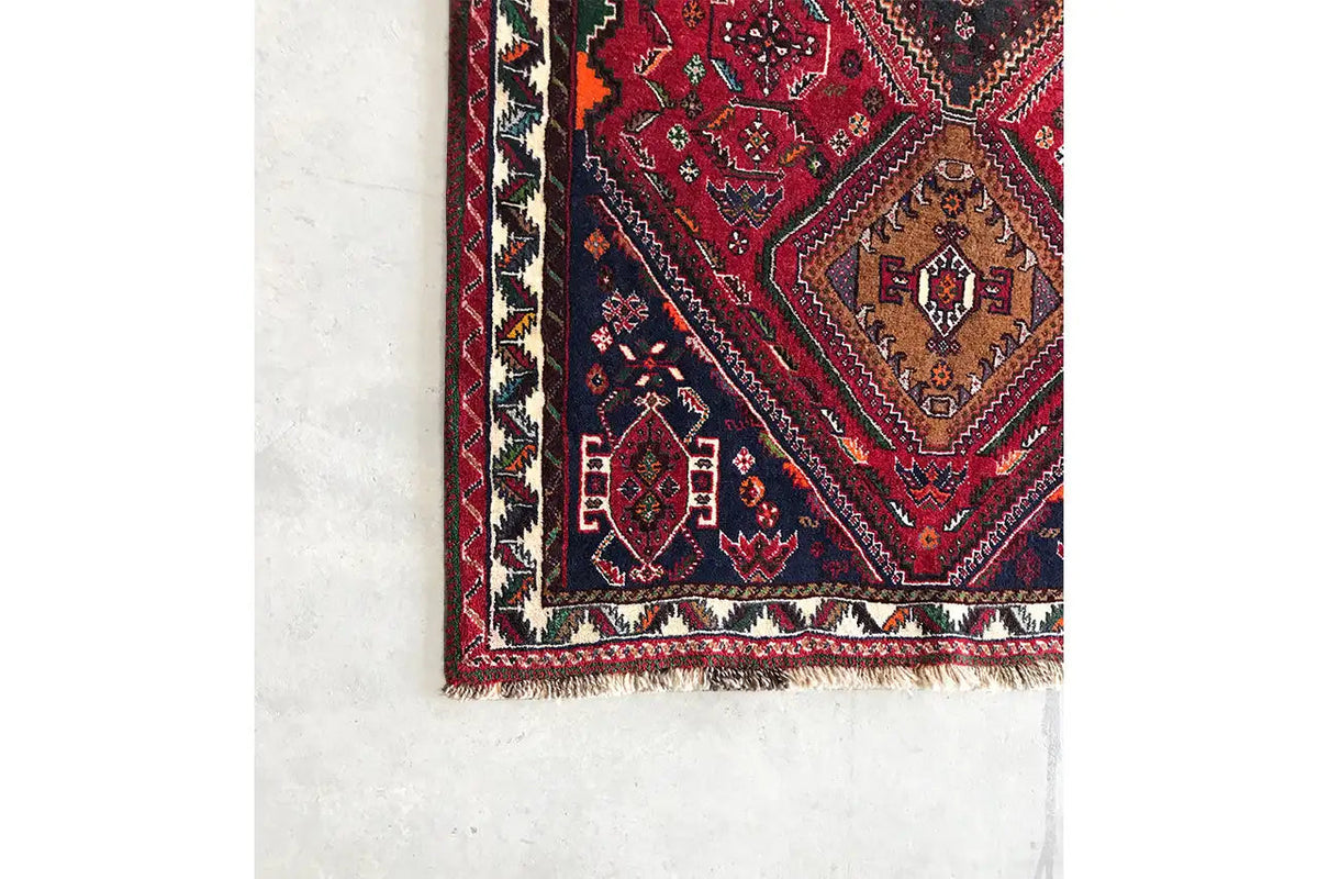 Oriental rug runner corner: red patterned field with border friezes, turquoise/green accents, fringes