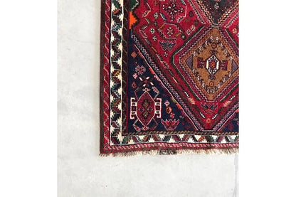 Oriental rug runner corner: red patterned field with border friezes, turquoise/green accents, fringes