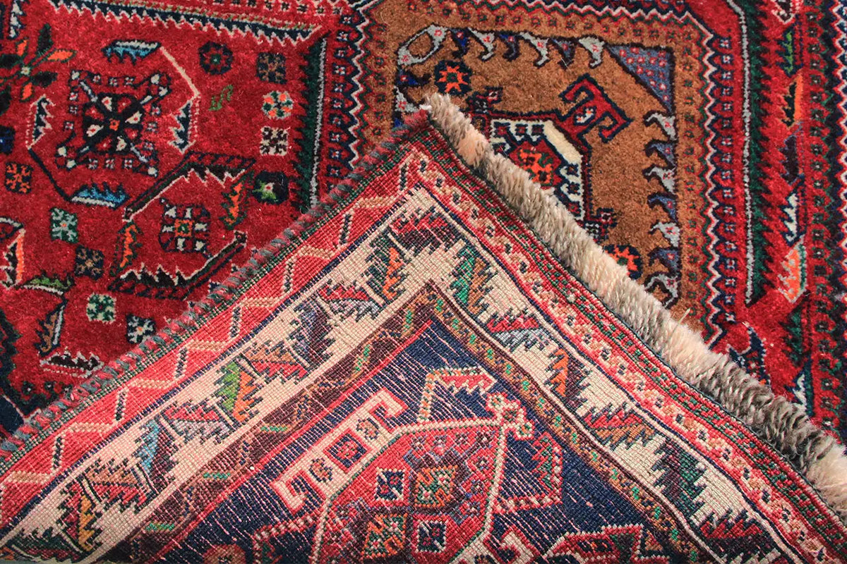 Oriental rug runner close-up: red ornament with beige areas, blue border, and pile fibers