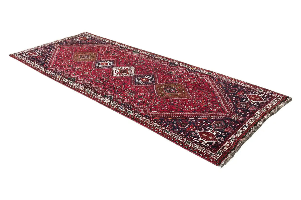 Rectangular rug with a red background and dark pattern, bound edges