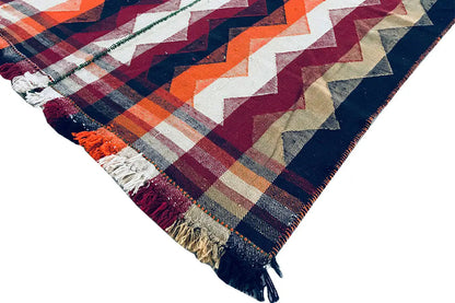 Jajim rug with zigzag stripes in blue, orange, and burgundy, rounded corner with fringe