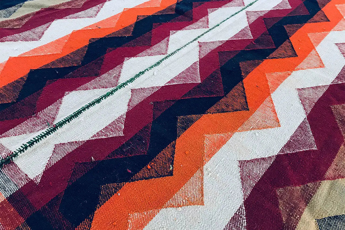 Close-up of a Jajim rug with a zigzag pattern in cream, dark blue, orange, and burgundy