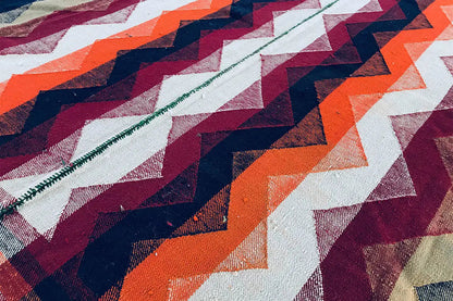 Close-up of a Jajim rug with a zigzag pattern in cream, dark blue, orange, and burgundy