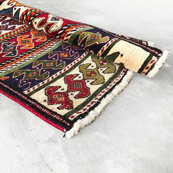 Qashqai rug by Poschti: edge view with fringes and multicolored ornamental bands