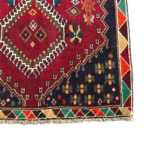 Detailed view of the rug: red ornamental pattern with colorful floral and diamond motifs