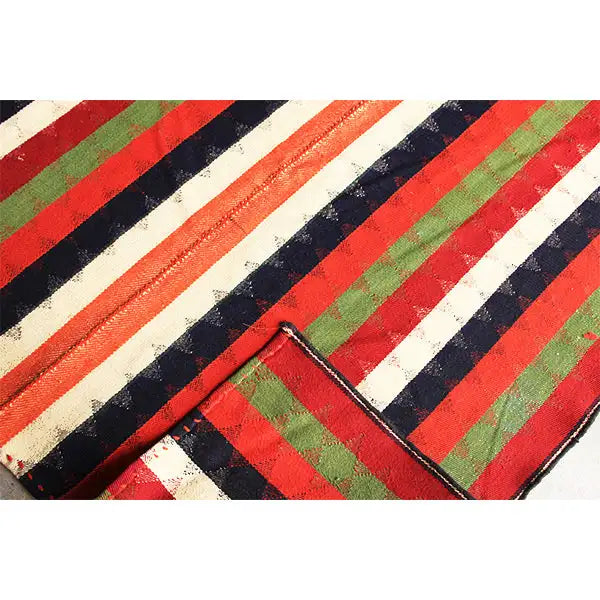 Jajim rug strips with a visible seam edge; red, cream, green and dark blue.