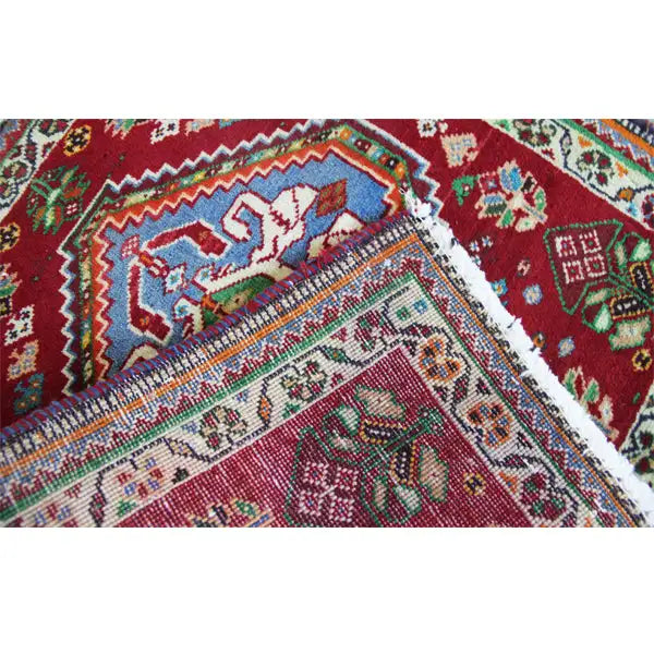Carpet detail with a relief texture and colorful patterns on a red background