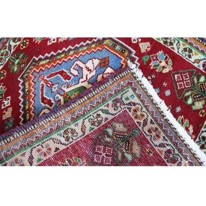 Carpet detail with a relief texture and colorful patterns on a red background