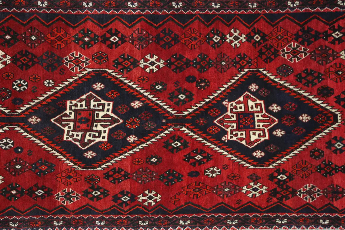 Runner with a large red central medallion, dark blue border pattern, and decorative fringe
