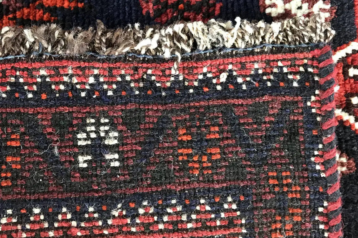 Runner edge with fringes and a delicate grid ornament in red and dark, framed in black