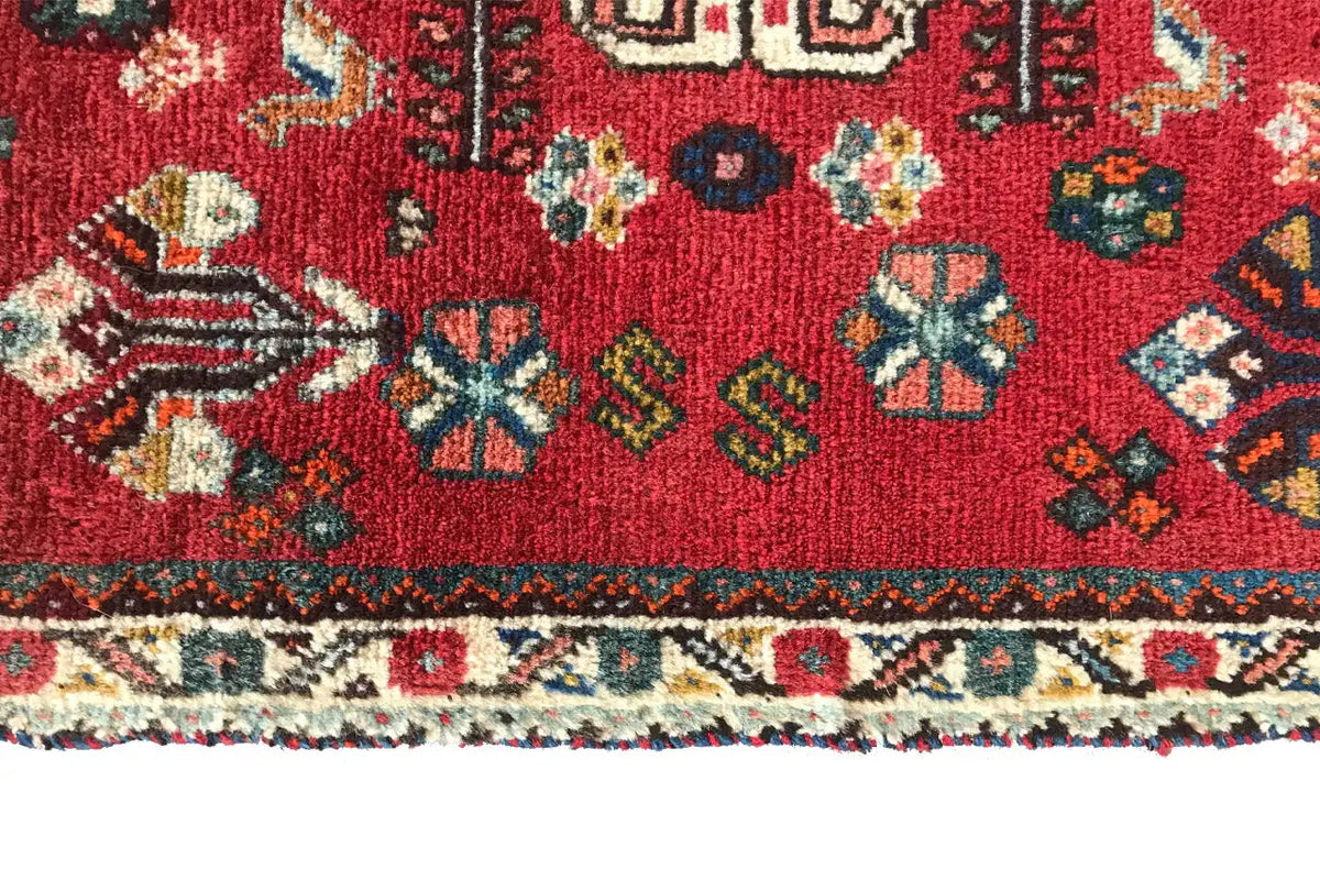 Close-up of the lower edge: red oriental rug with a border pattern and fringes