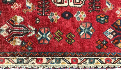 Close-up of the lower edge: red oriental rug with a border pattern and fringes