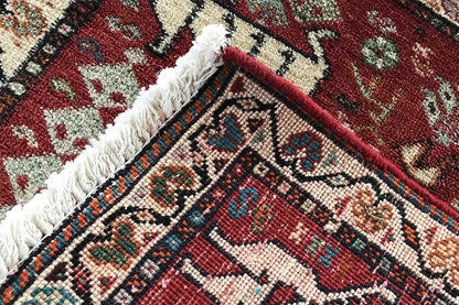 Corner of a red carpet with a decorative studded frame and frayed edge