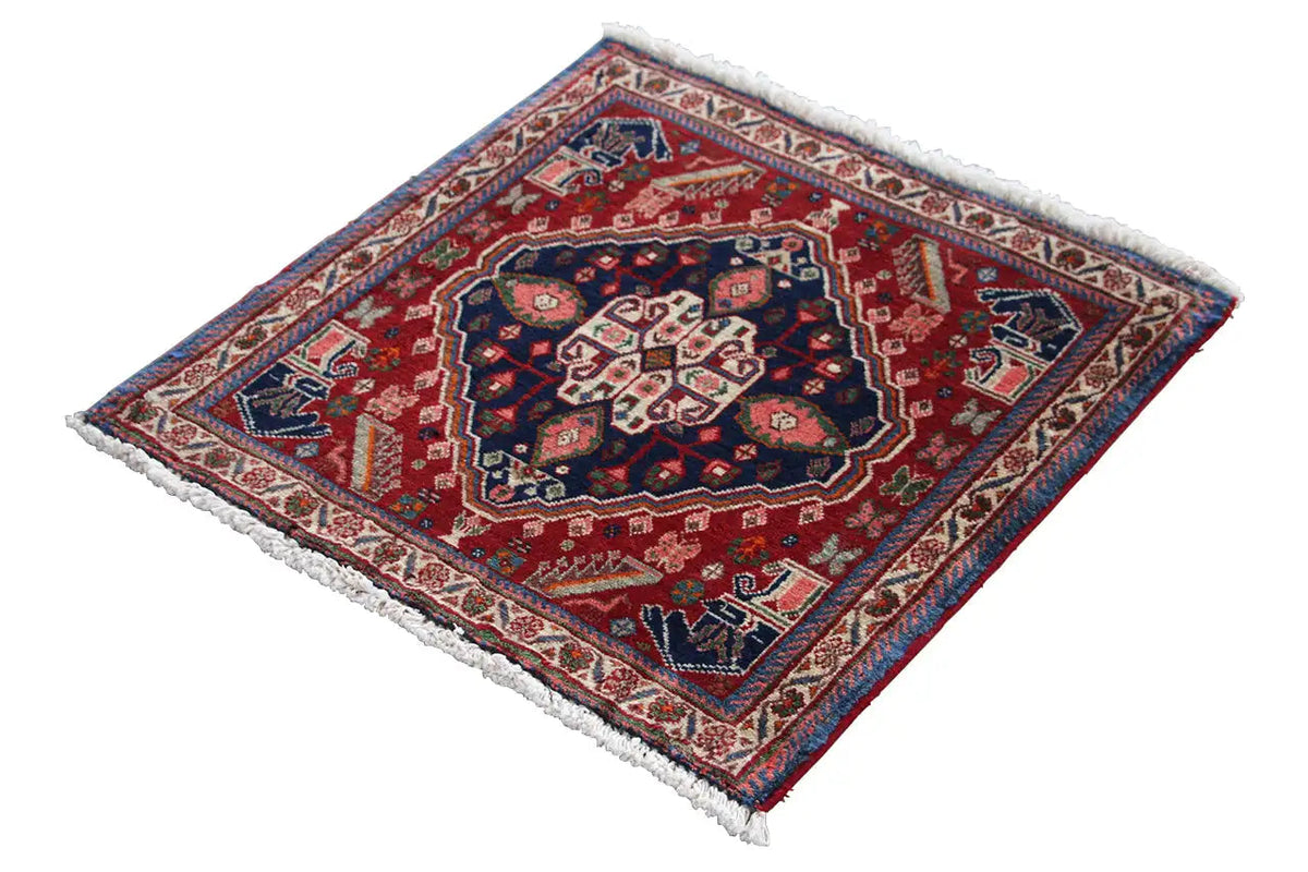 Oriental rug with a red border and dark blue center, diagonal view, fringes