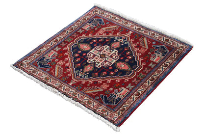 Oriental rug with a red border and dark blue center, diagonal view, fringes