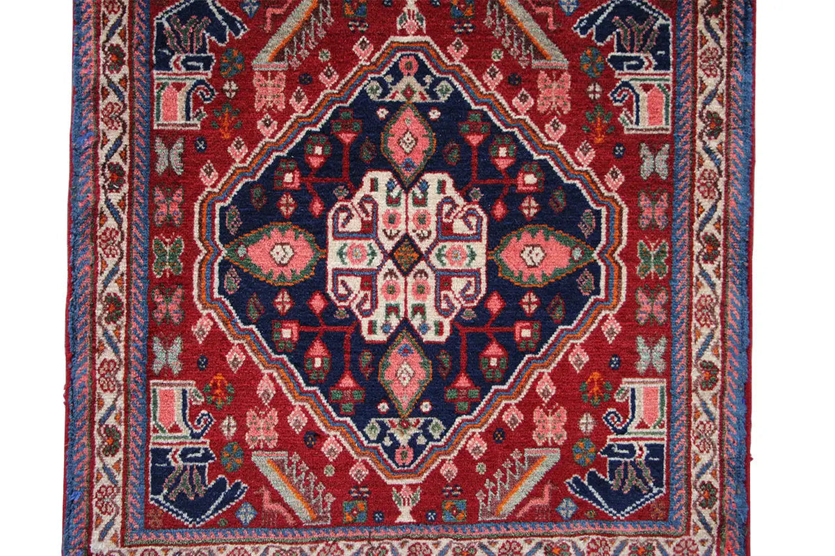 Oriental rug detail: red field with a blue ornamental border and medallion pattern
