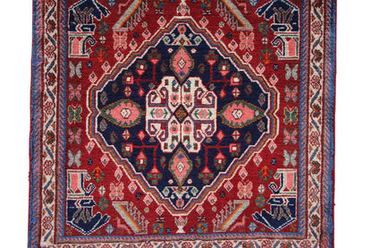 Oriental rug detail: red field with a blue ornamental border and medallion pattern