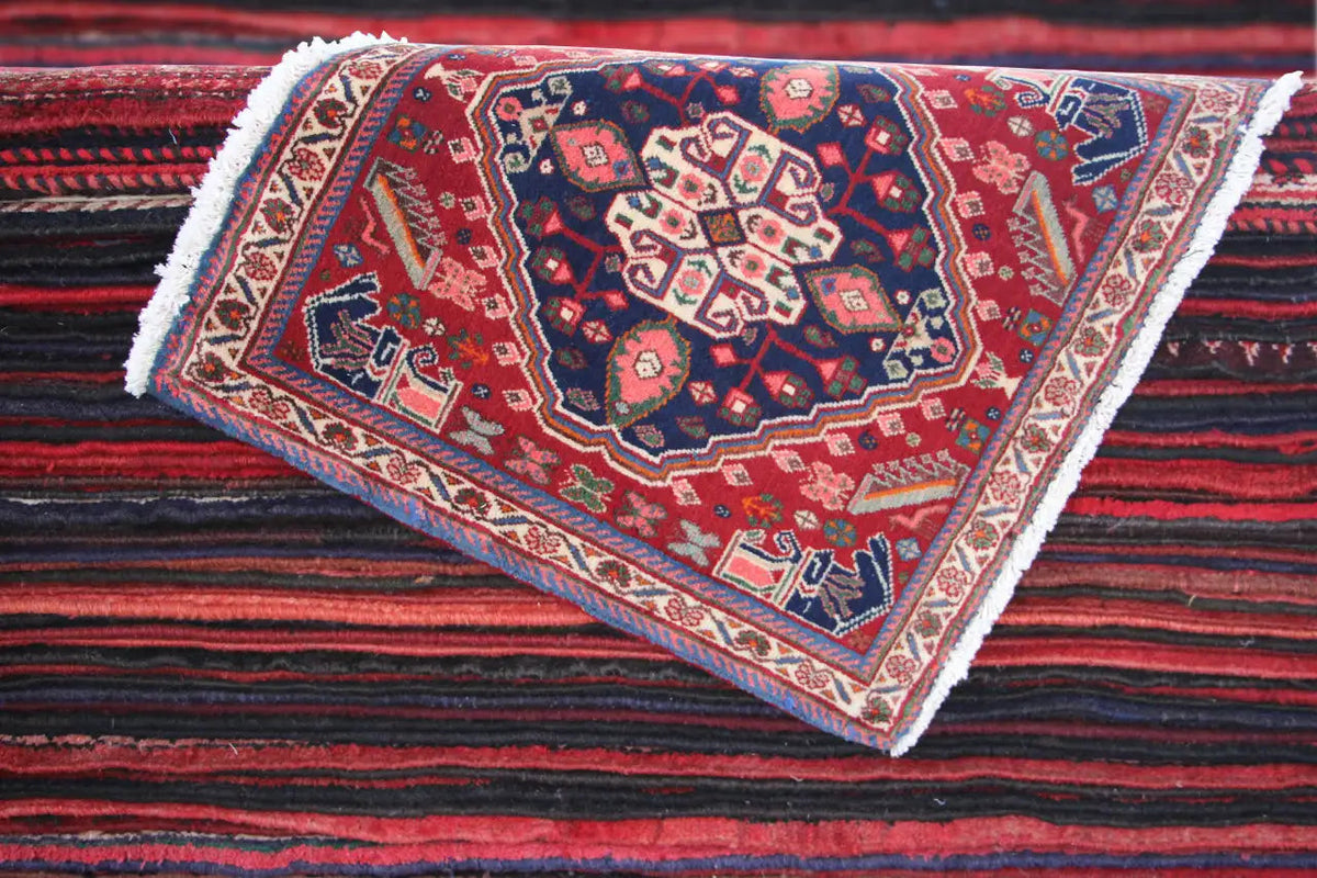 Oriental rug viewed diagonally, red field with medallion pattern, white fringes