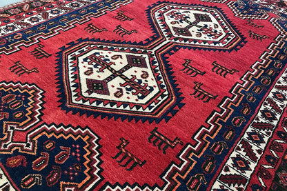 Oriental rug with a red background and blue zigzag border; central white medallions.