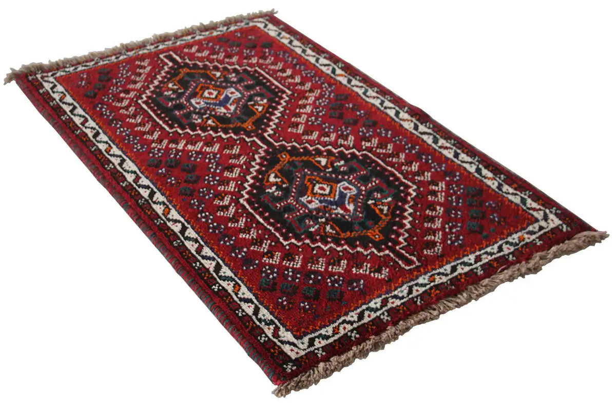 Oriental rug with a red geometric design and light borders, fringes visible
