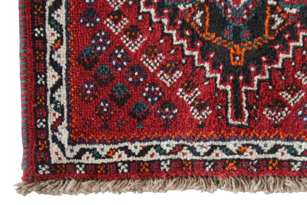 Close-up: red carpet edge with decorative trim, multicolored patterns, and fringe