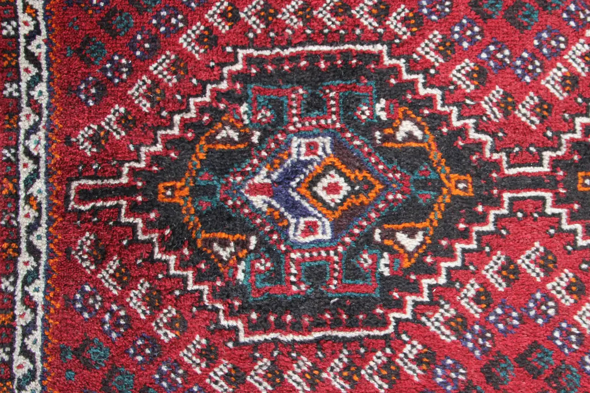 Close-up of carpet: red center with blue-gray diamonds, delicate ornamentation
