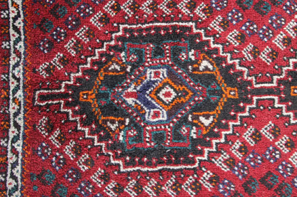 Close-up of carpet: red center with blue-gray diamonds, delicate ornamentation