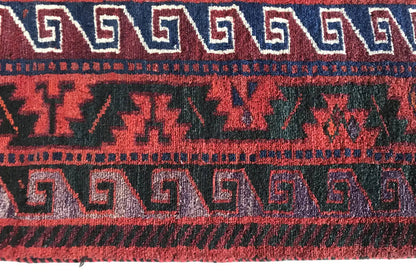 Close-up of a carpet edge with a repeating pattern in white, red, and dark blue