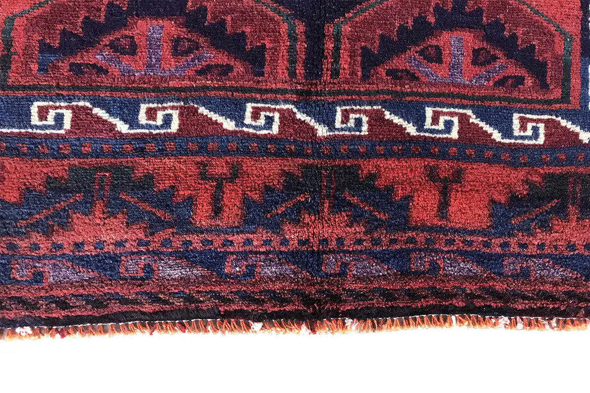 Close-up of a carpet edge with a colorful border and fringe, red-dark blue
