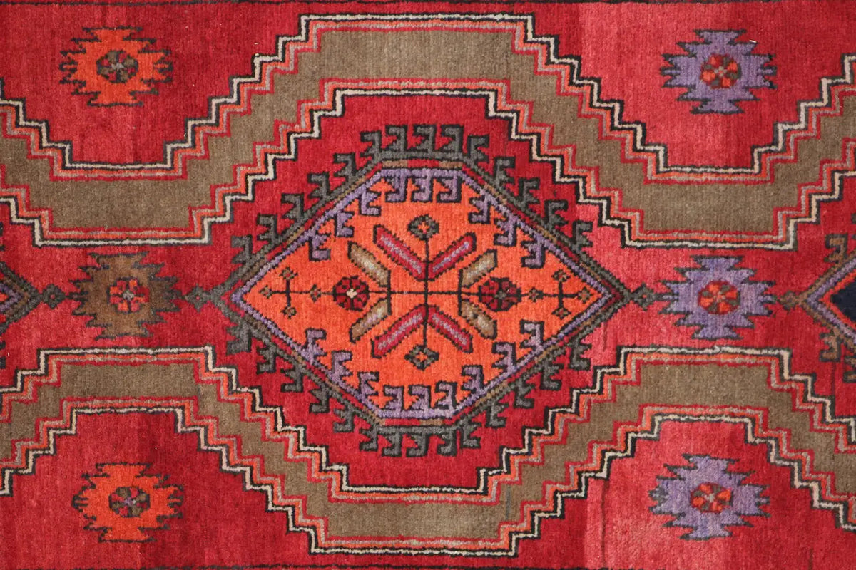 Close-up of the Hamadan rug: red field with a medallion, diamonds, and surrounding decorative bands