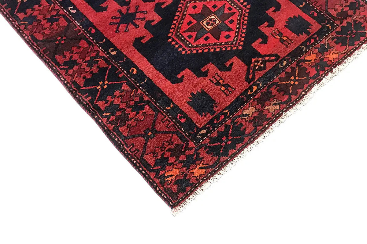 Detail of a red runner rug with blue border trim, fringes, and a geometric pattern.